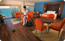 A housekeeper vacuuming a bright hotel room