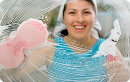 A cleaner smiling while wiping a glass window